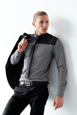 Beyaz arka planda poz veren siyah takım elbiseli yakışıklı bir adamın portresi.