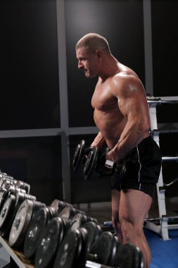 Yakışıklı kaslı adam spor salonunda çalışıyor ve poz veriyor.
