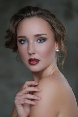 Gri arka planda makyajlı hoş bir genç kadın.