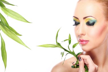Sanatsal makyajlı ve bambu yapraklı güzel bir sarışın.