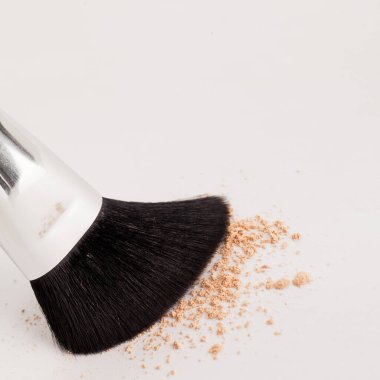 Beyaz arka planda bej tozuyla doğal makyaj fırçası