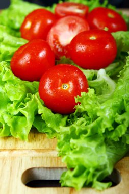 Salata yapraklarının üzerinde duran taze ve ıslak domatesler.
