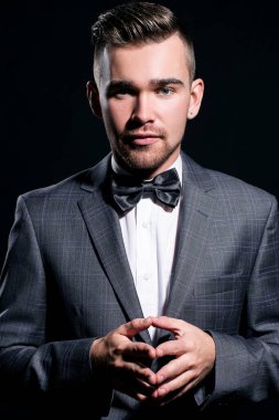 şeritli bir arka plan üzerinde koyu takım elbise ve kravat takan yakışıklı adam sakallı bir poz