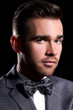 şeritli bir arka plan üzerinde koyu takım elbise ve kravat takan yakışıklı adam sakallı bir poz