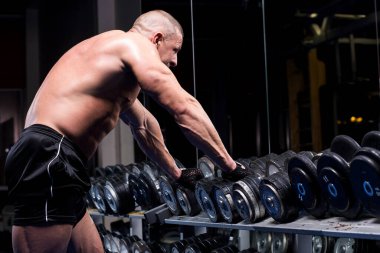 Yakışıklı kaslı adam spor salonunda çalışıyor.