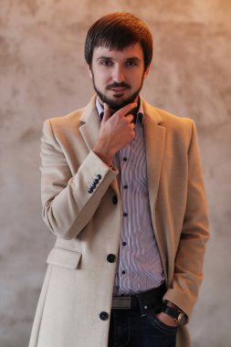 Palto giyen yakışıklı adamın stüdyo portresi.