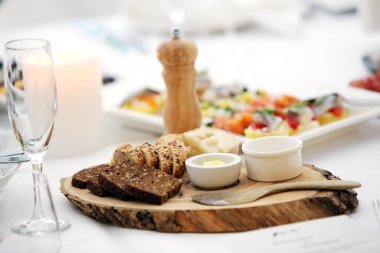 Ekşi kremalı iki farklı ekmek ve tahta bir tabakta duran tahta bir kaşık.