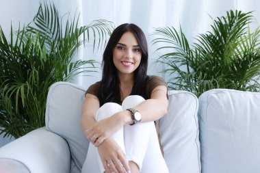 Evdeki kanepede oturan güzel bir kadın.