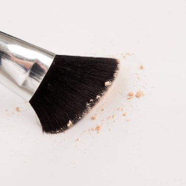 Beyaz arka planda bej tozuyla doğal makyaj fırçası