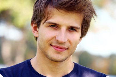 Parkta poz veren yakışıklı genç adamın portresi.