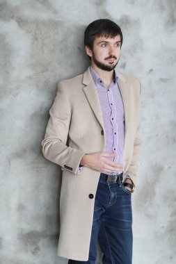 Palto giyen yakışıklı adamın stüdyo portresi.