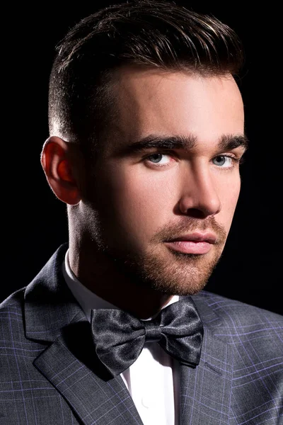 şeritli bir arka plan üzerinde koyu takım elbise ve kravat takan yakışıklı adam sakallı bir poz