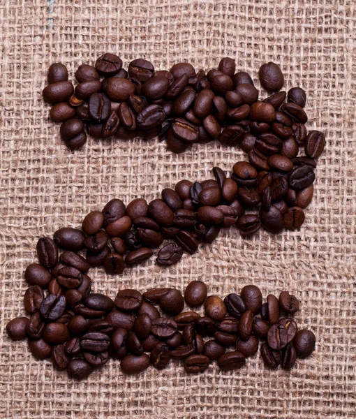 Kahve çekirdekleri kumaş çuvalının üstünde.