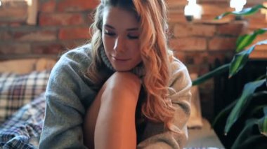 Evde yatakta kameraya poz veren bir kadın. 