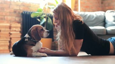 Evde köpekle oynayan güzel genç bir kadın.