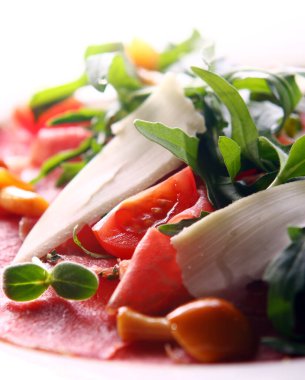 Biftek carpaccio roka ve mantarla servis edilir.