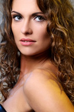 kıvırcık saçlı ve hafif bir arka plan üzerinde poz çıplak omuzlarına güzel esmer bir kadın portresi