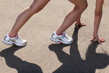 Kadın elleri ve bacakları asfalt zemin üzerinde spor ayakkabılarla