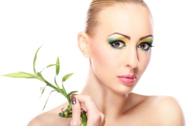 Sanatsal makyajlı ve bambu yapraklı güzel bir sarışın.