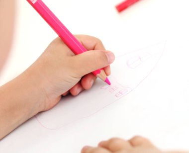 Kağıda renkli kalemlerle resim çizen sevimli küçük kız.