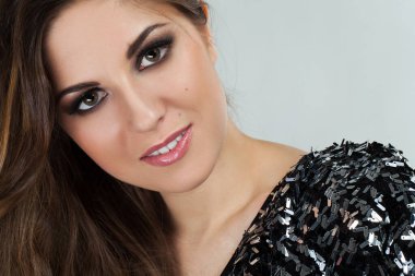 Bukleli ve etkileyici makyajlı güzel bir genç kadının portresi.