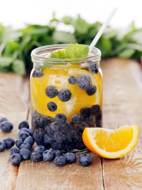 Çilek ve limonla dolu bir kavanoz. Tahta bir yüzey üzerinde kamışla.