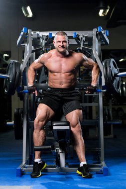 Yakışıklı kaslı adam spor salonunda çalışıyor.