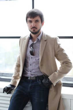 Palto giyen yakışıklı adamın stüdyo portresi.