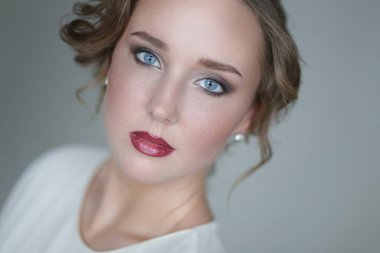 Gri arka planda makyajlı hoş bir genç kadın.