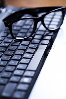 Üzerinde gözlük olan parlak bir dizüstü bilgisayarın yakın plan fotoğrafı.