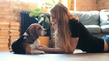 Evde köpekle oynayan güzel genç bir kadın.