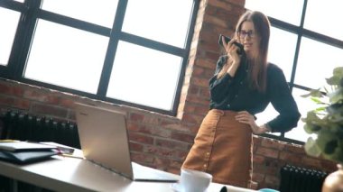 İş kadını ofiste akıllı telefondan konuşuyor.