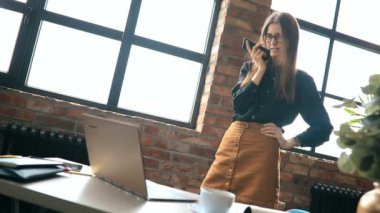 İş kadını ofiste akıllı telefondan konuşuyor.