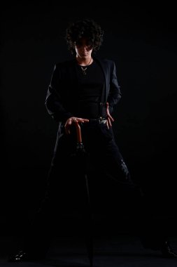 Genç ve çekici Latin çocuk karanlık arka planda dans ediyor.