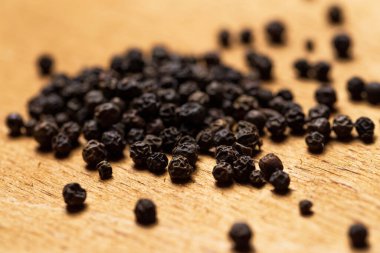 Kahverengi bir masada siyah biber yığını.