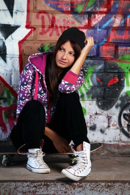 grafiti ile duvara kaykay üzerinde oturan genç ve güzel kız