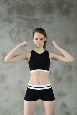 Spor takım elbiseli sıska bir kadın gri duvar arkası, spor ve spor konsepti üzerinde poz veriyor. 