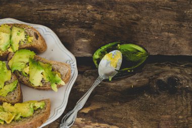Tahta bir masada nefis avokado sandviçi.
