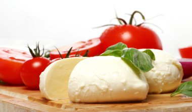 Taze ve lezzetli domatesler, fesleğen ve mozzarella tahtada.