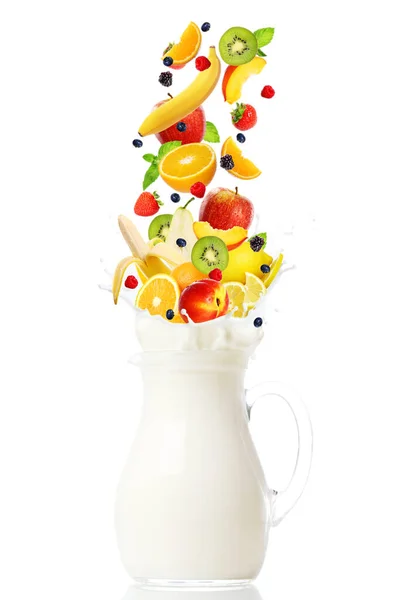 Fresh fruits falling into the jar with milk over white background