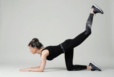 Beyaz arka planda egzersiz yapan genç bir kadın.