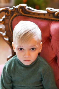 Kırmızı kanepede oturan genç çocuk