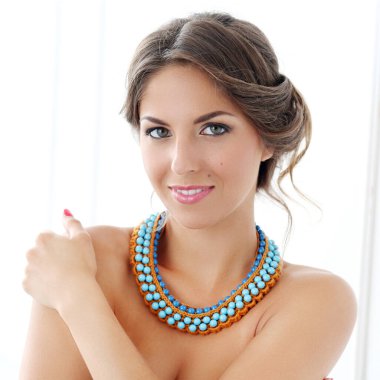 Beyaz arka planda boncuklu kolyesi olan güzel bir kadının portresi.