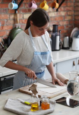 Genç ve güzel bir kadın mutfakta yemek pişiriyor. El yapımı yemek.