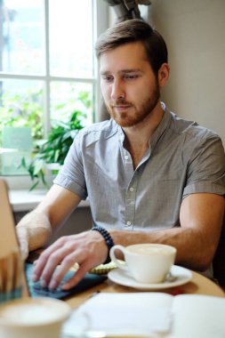genç erkek serbest meslek sahibi Online kafede dizüstü kullanma ve içme kahve sohbet