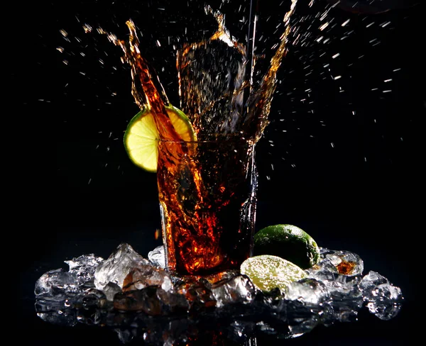 黒の背景に水と緑の石灰のスプラッシュと新鮮なコーラ飲料 — ストック写真