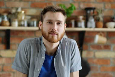 Sakallı yakışıklı genç adam mutfakta poz veriyor.