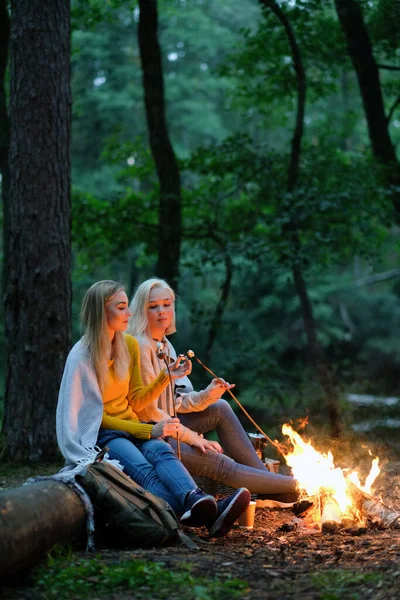 Seyahat ve keşfetmek. Ormandaki şenlik ateşi yakınındaki iki genç güzel kadın
