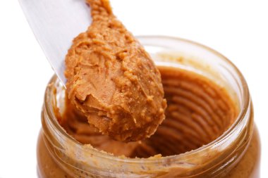 Masanın üzerinde bıçak olan fıstık ezmesi şişesi.