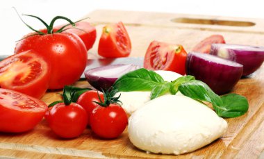 Taze ve lezzetli domatesler, fesleğen ve mozzarella tahtada.